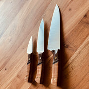 TANZO CUTLERY set of three handcrafted chef knives with polished steel blades and ergonomic two-tone wood handles.