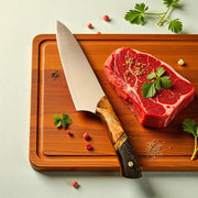 TANZO CUTLERY professional chef knife with a handcrafted wood and dark resin handle resting on a wooden cutting board